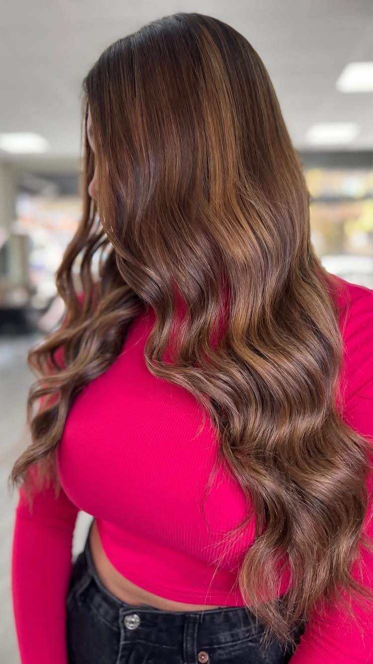 Long wavy brown hair with blended blonde caramel highlights on woman
