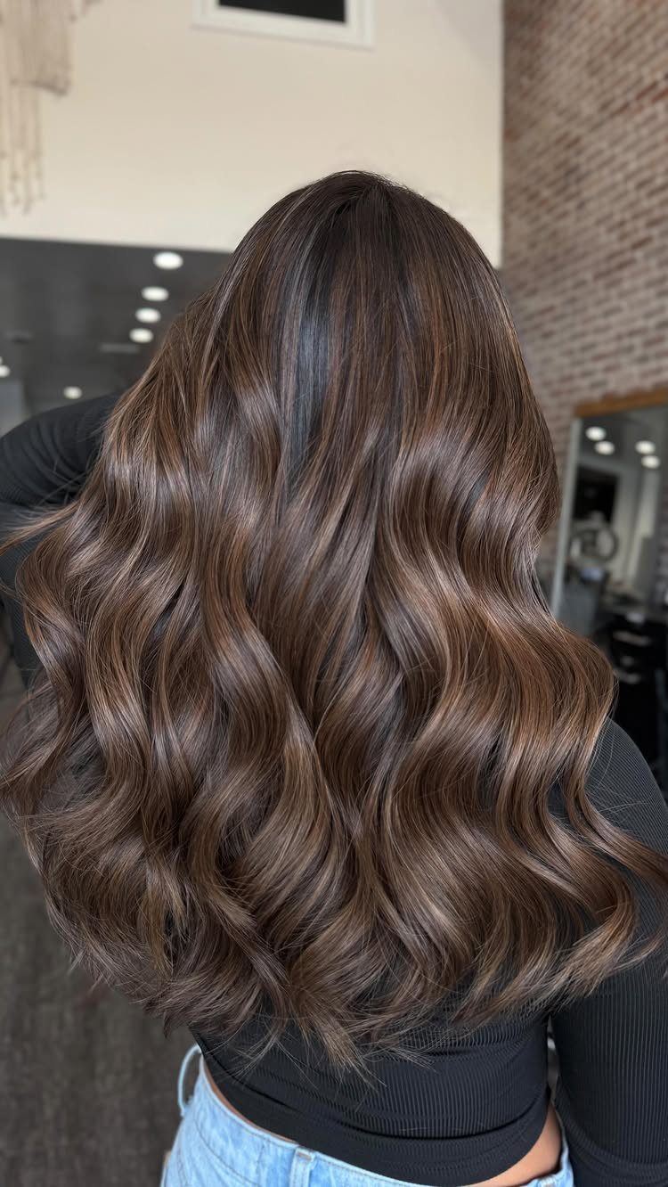 Long wavy brown hair with fine sun-kissed highlights in a salon