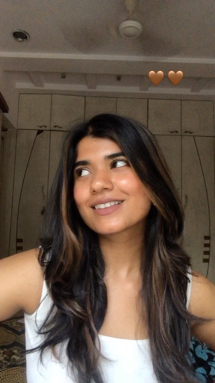 Woman with long dark hair and subtle caramel highlights framing her face