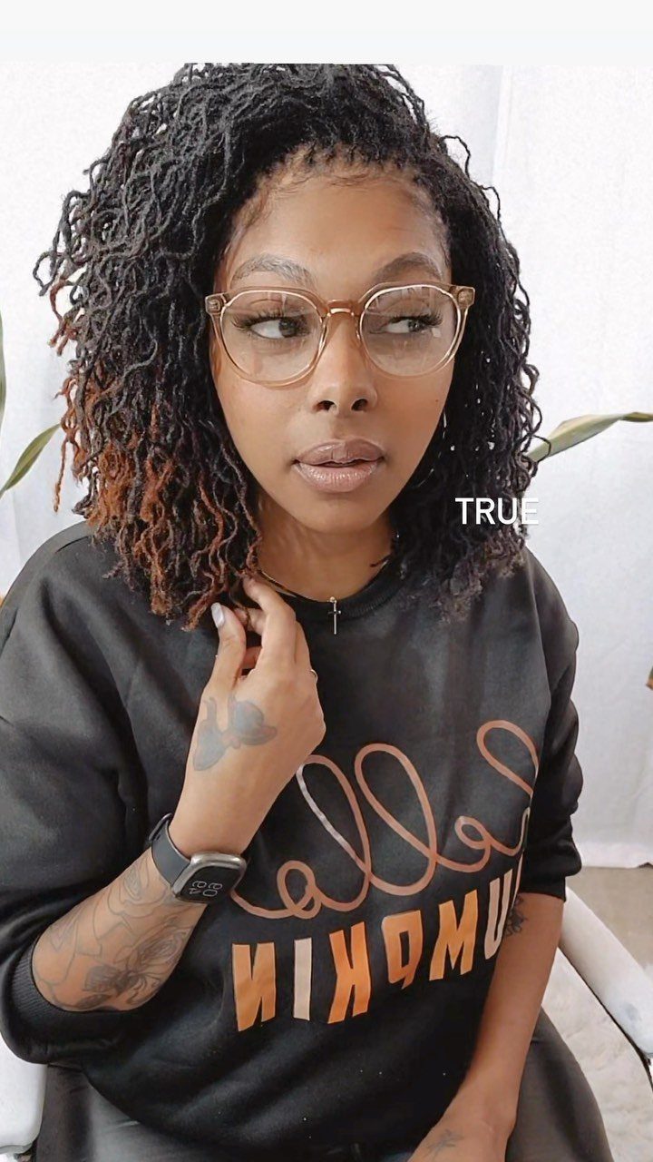 Woman with dark curly hair and subtle reddish-brown highlights wearing glasses