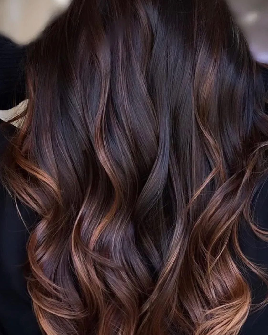 Dark auburn wavy hair with subtle caramel balayage highlights