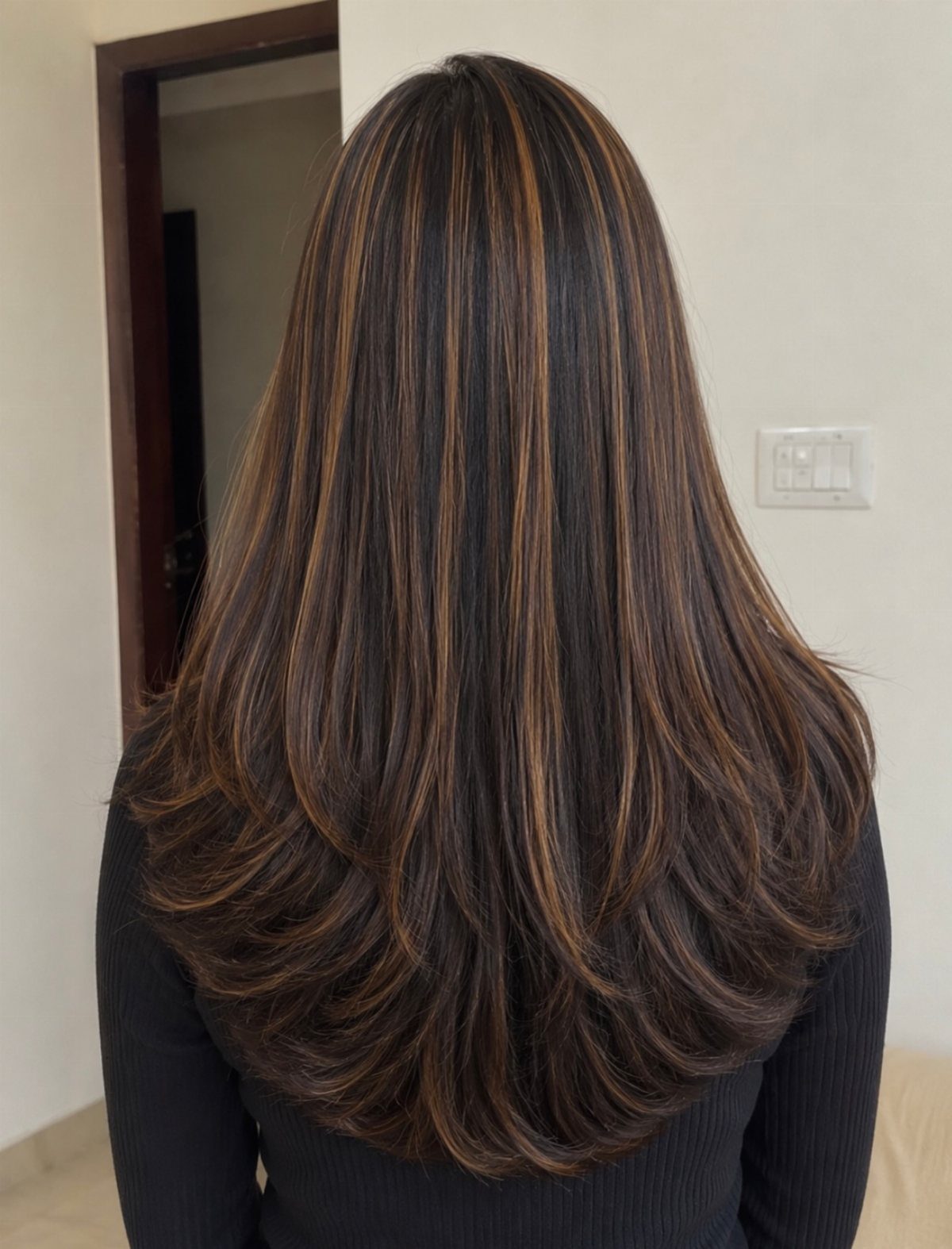Long dark brown hair with warm caramel-brown highlights and layered curled ends