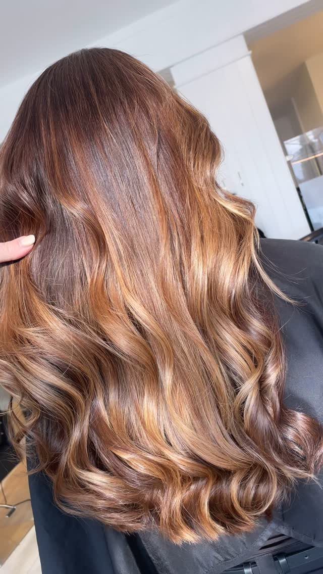 Long brown waves with caramel highlights concentrated through the lower lengths