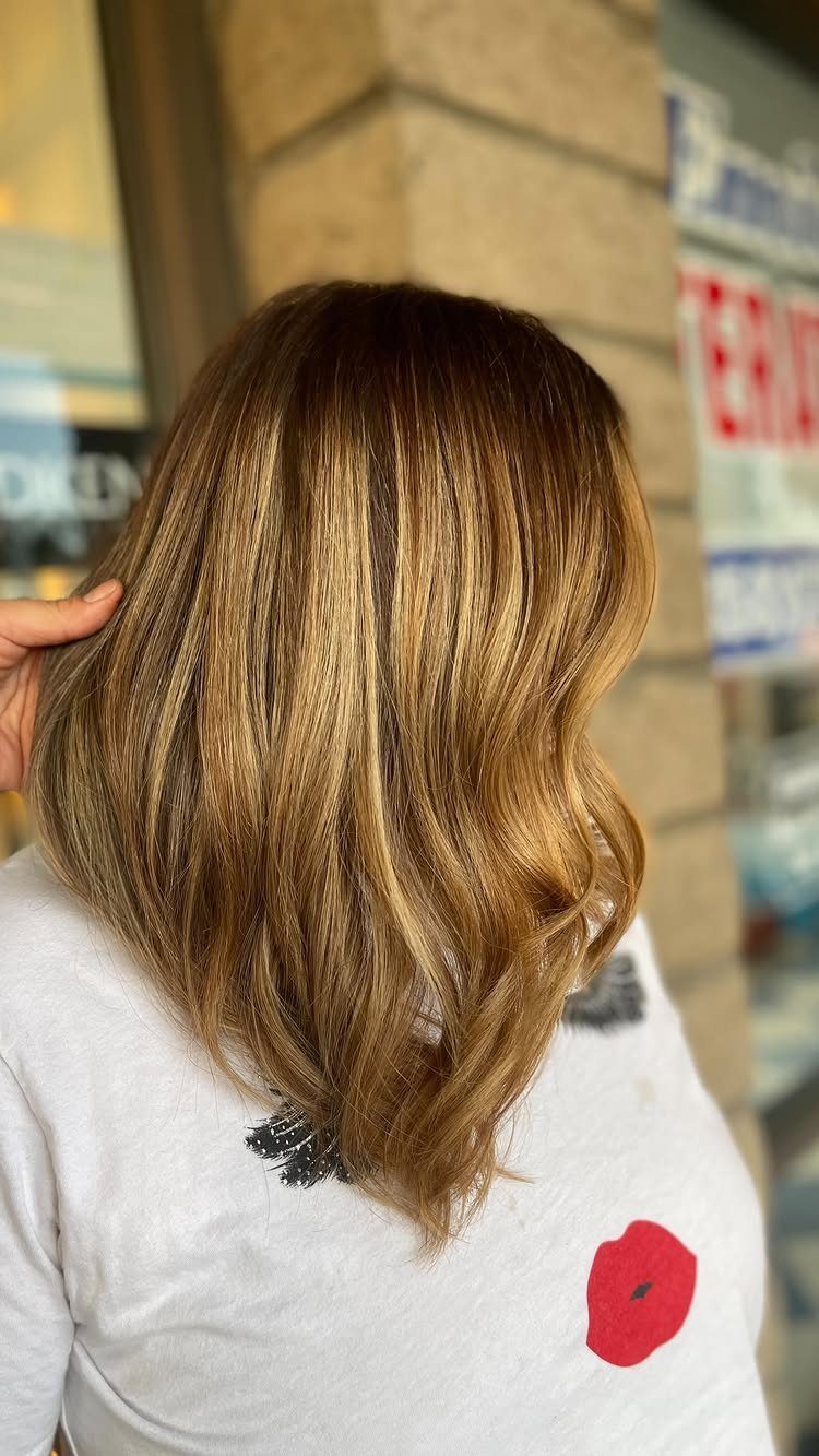 Long wavy brown hair with blended golden-blonde ombre balayage highlights