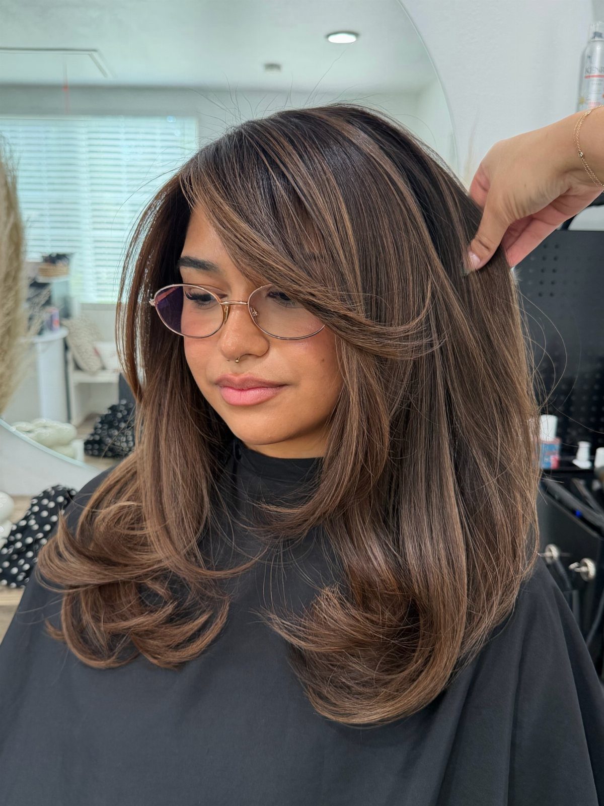 Medium-brown layered hair with caramel highlights styled in soft, voluminous waves