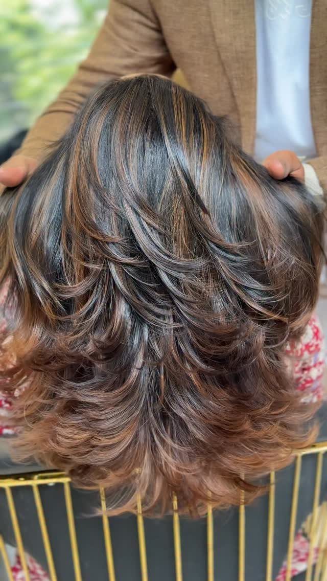 Layered mocha-brown hair with caramel highlights and curled ends