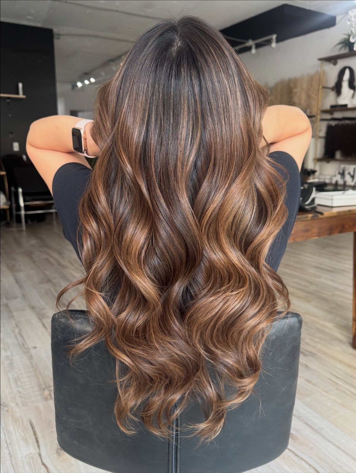 Long wavy dark brown hair with blended caramel balayage in a salon