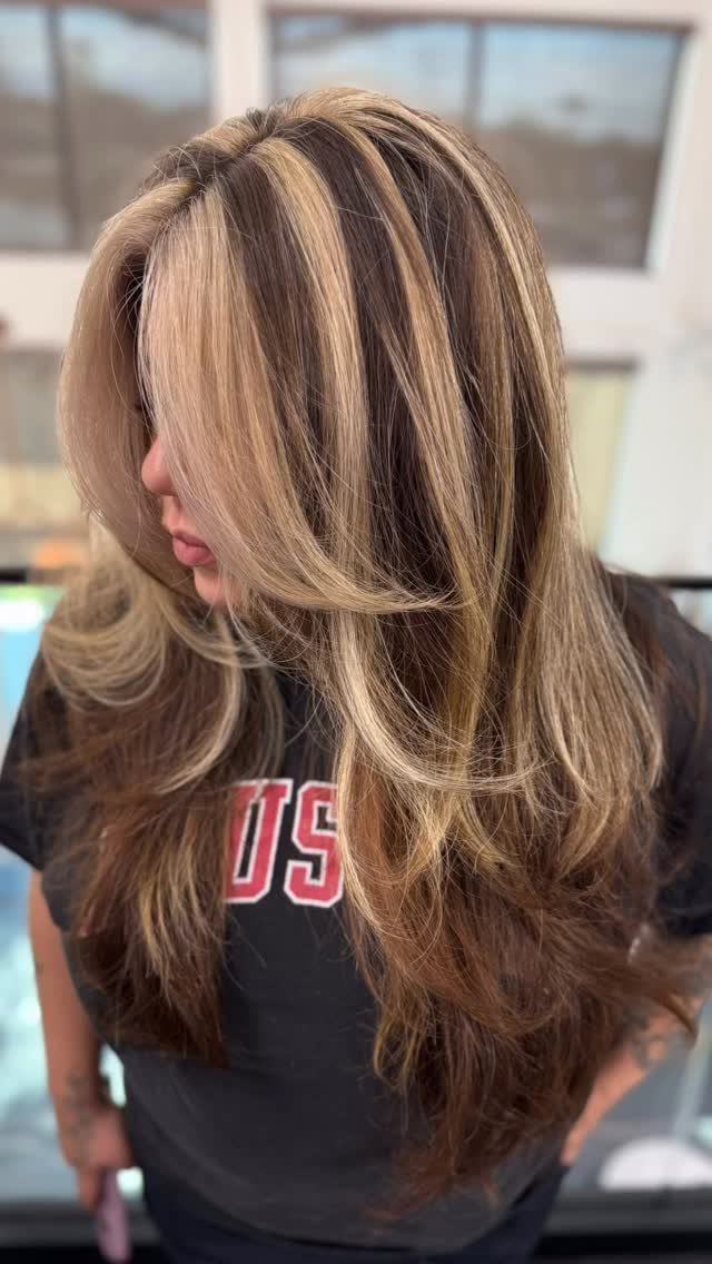 Long brown hair with broad blonde highlights styled in voluminous loose curls