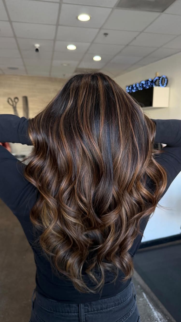 Long dark brown curls with fine light brown vertical highlights in a salon
