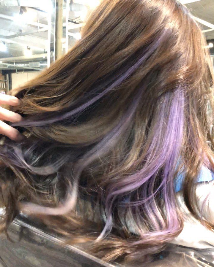 Long brown hair with lavender highlights in loose waves at a salon