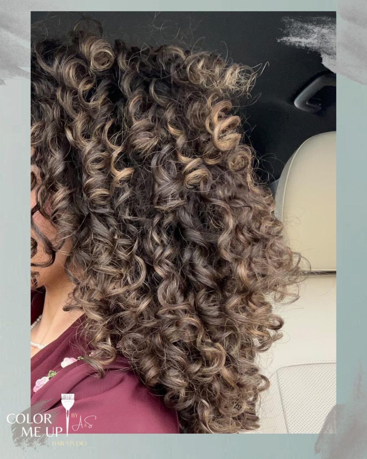 Dark brown curls with warm blonde and caramel highlights beside a car seat