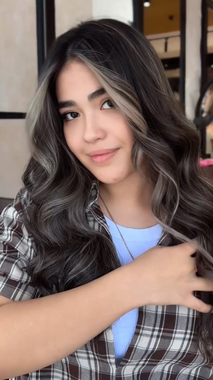 Woman with long dark curls and lighter highlights framing her face