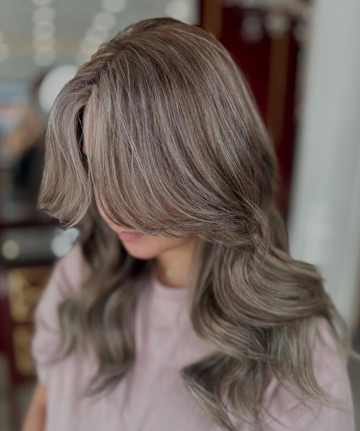 Person showing cool grayish ash-blonde layered hair with side-swept bangs