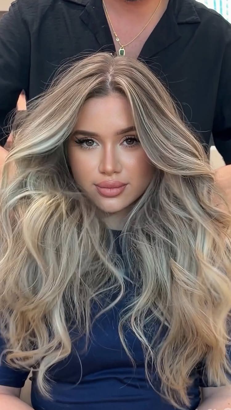 Woman with long, wavy blonde balayage and softly blended highlights