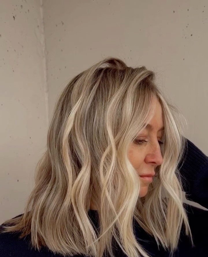 Woman showing wavy butter blonde hair with darker roots and bright creamy highlights