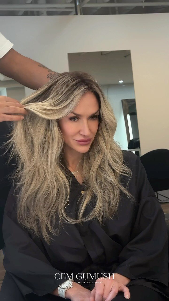 Woman with long, wavy blonde hair and soft highlights in a salon chair