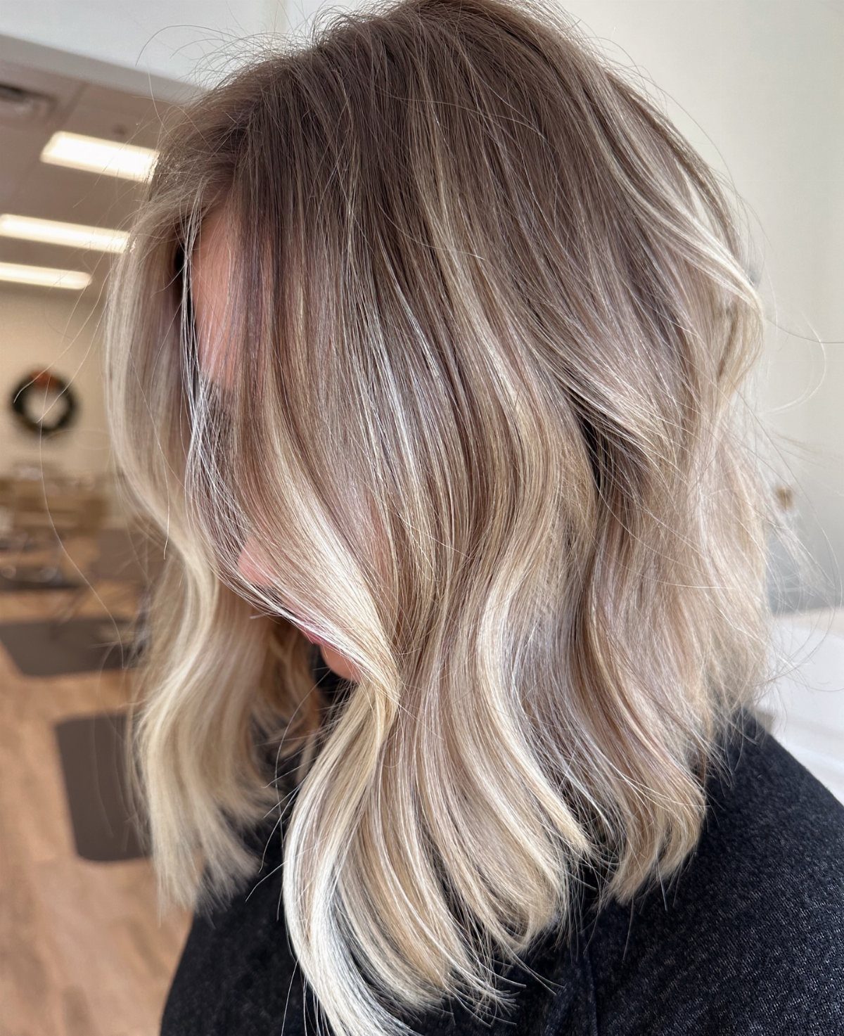 Wavy shoulder-length hair with cool ashy blonde highlights and darker roots