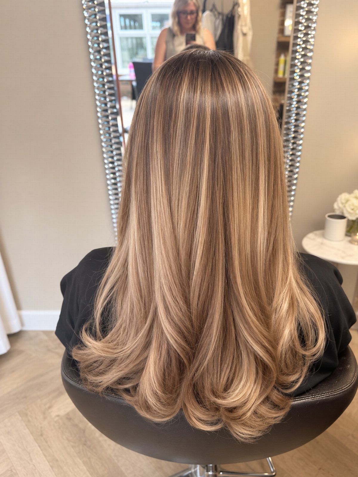 Cool-toned blonde hair with soft highlights and curled ends in a salon