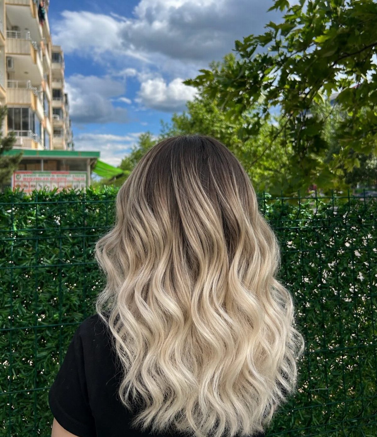 Wavy hair fades gradually from dark roots to pale blonde ends
