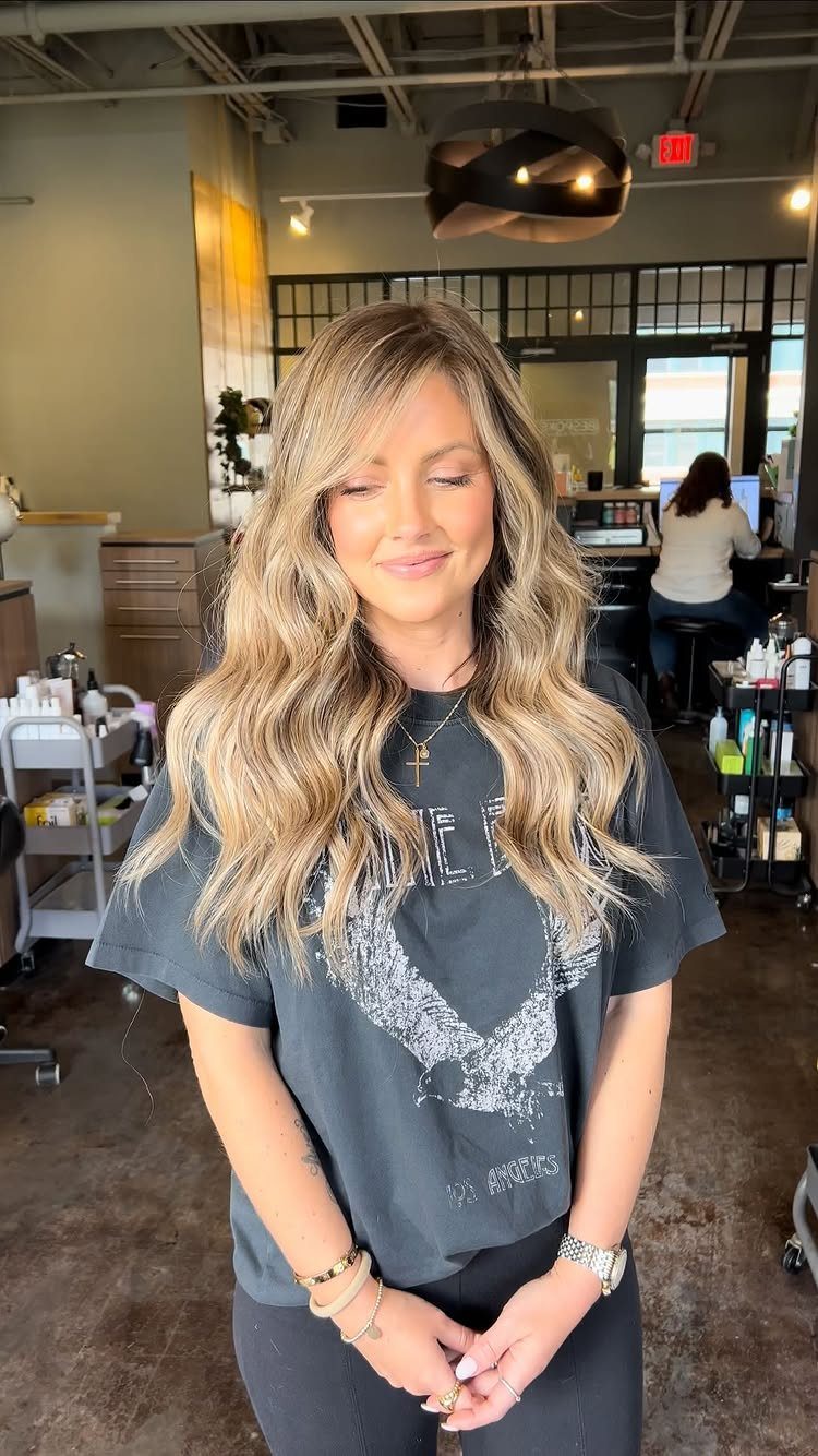 Woman with long highlighted blonde waves posing in a bright salon