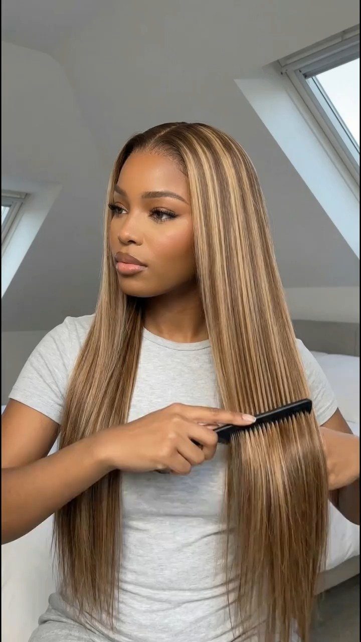 Woman combing long brown hair with warm honey blonde highlights