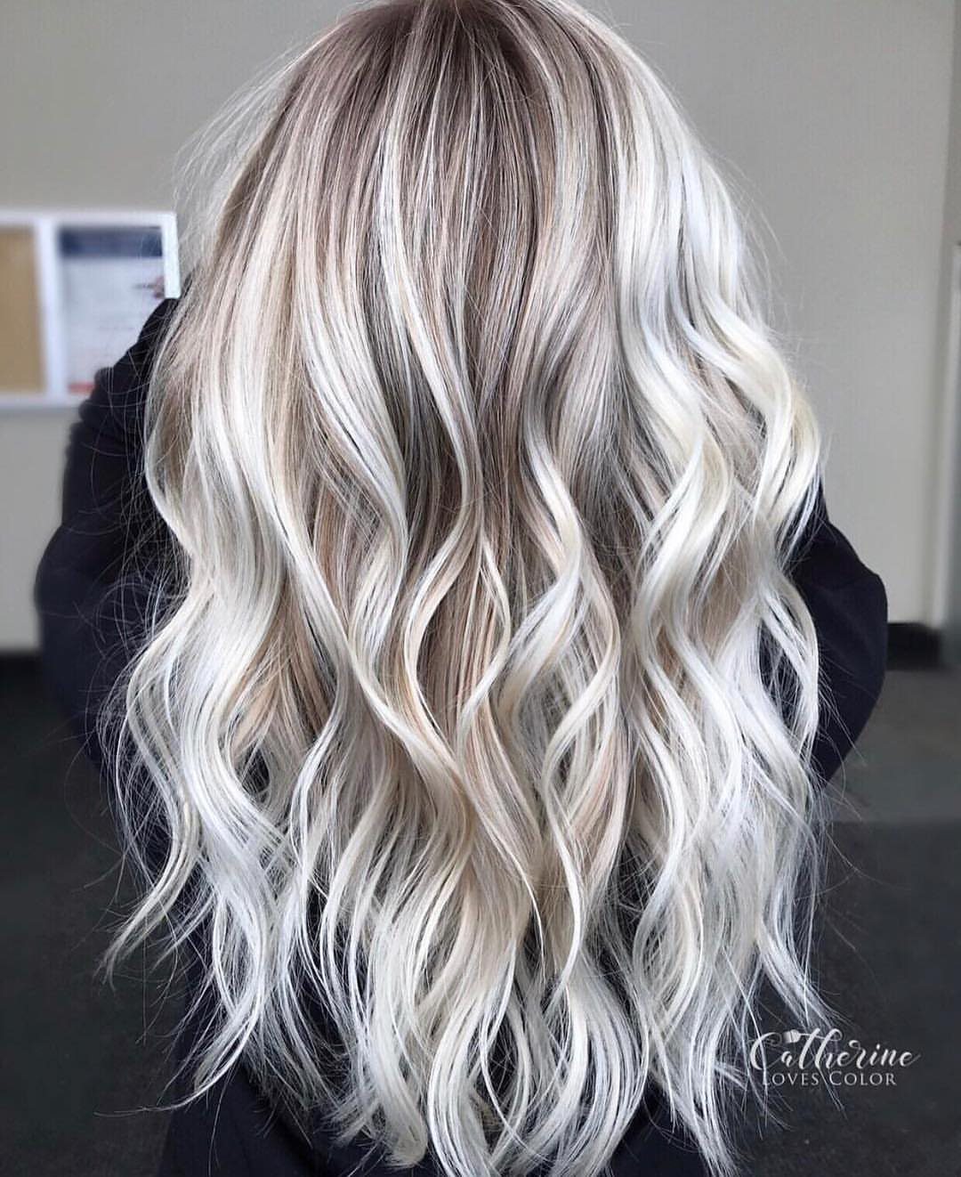 Long wavy hair with icy platinum blonde highlights and darker roots