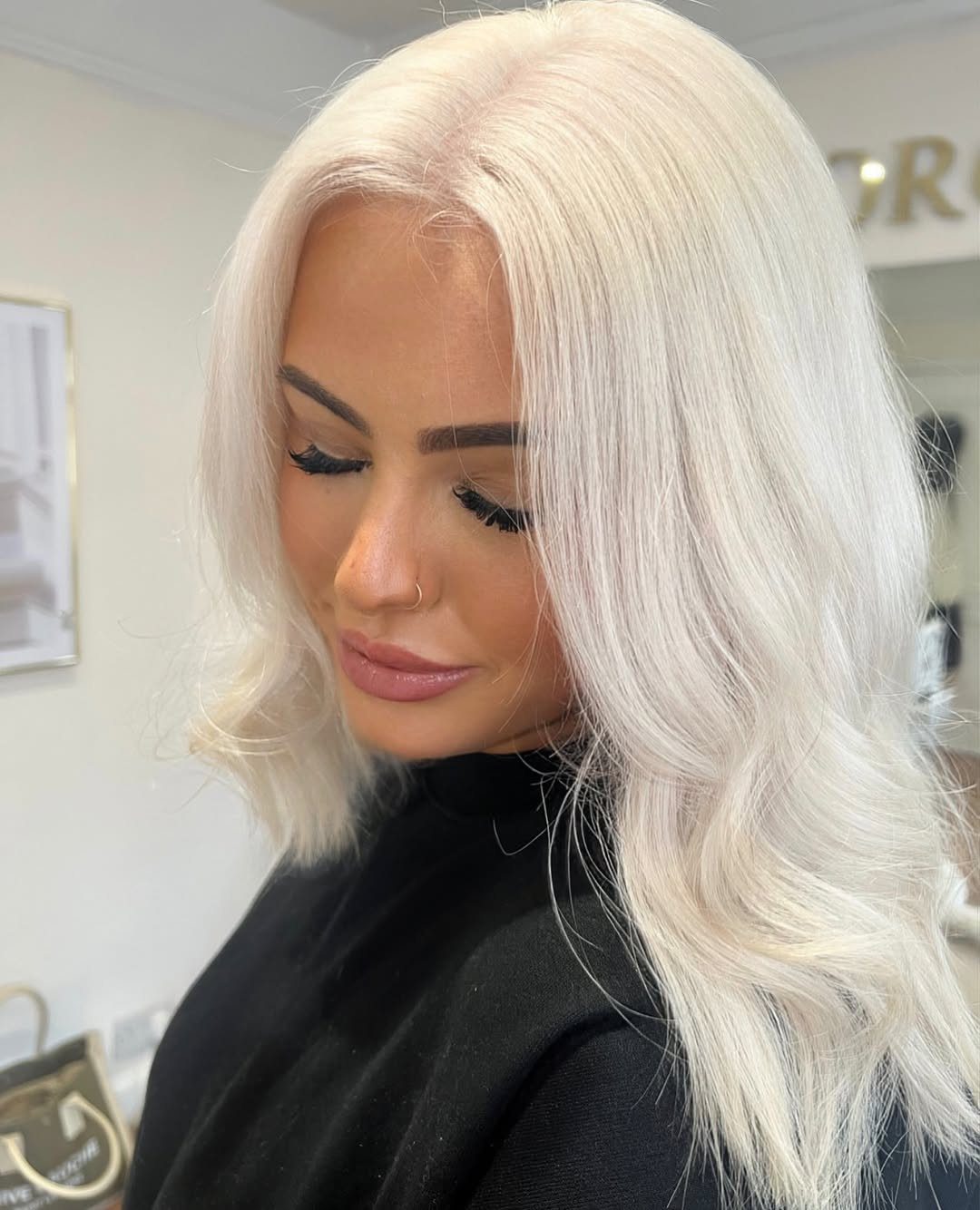 Woman with long platinum blonde hair and softly curled ends in a salon