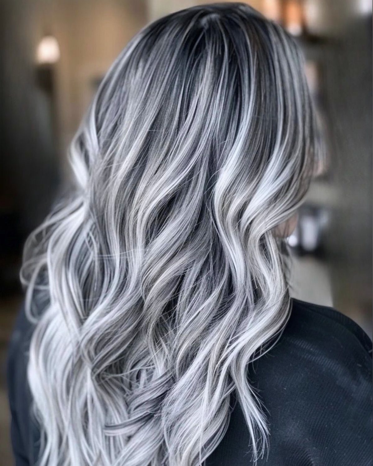 Wavy silver-white hair with dark roots cascading down the back