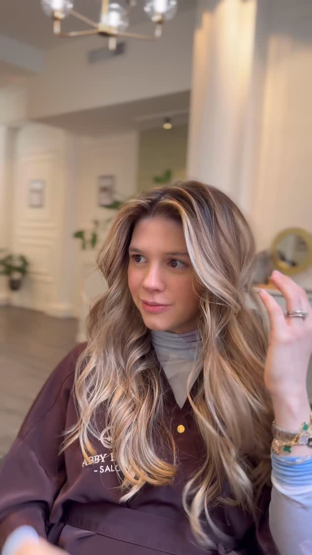 Woman showing long wavy brown hair with bright blonde balayage highlights