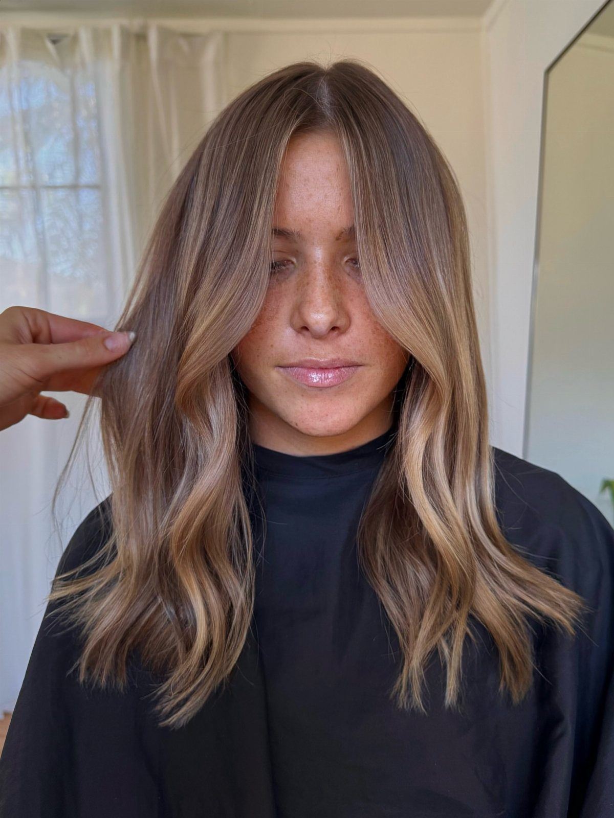 Long wavy brown hair with light blonde balayage highlights in a salon