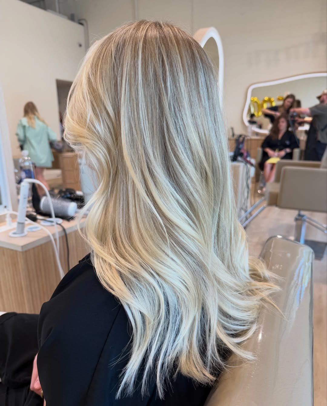 Blonde layered hair shows darker roots fading into bright, pale ends