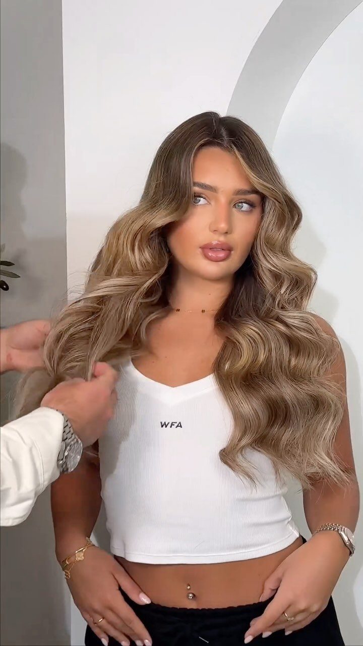 Woman with long wavy brown hair and blended blonde highlights