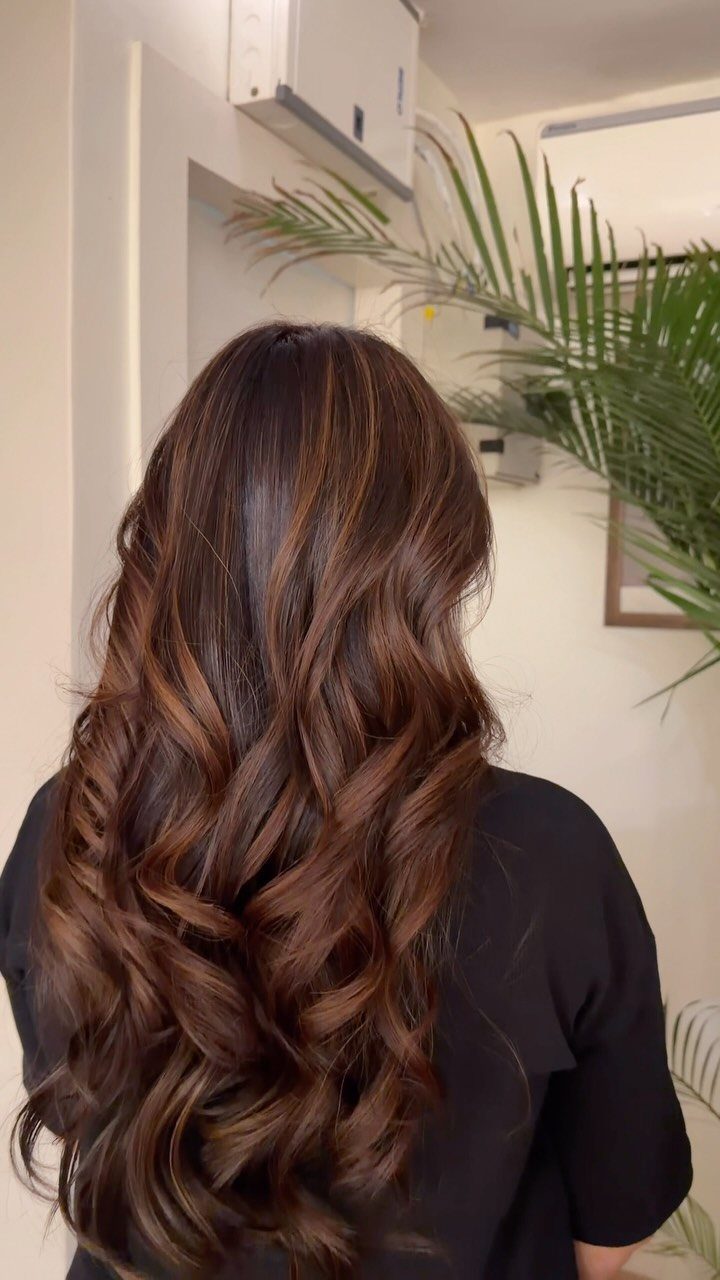 Long wavy brown hair with subtle reddish-brown highlights