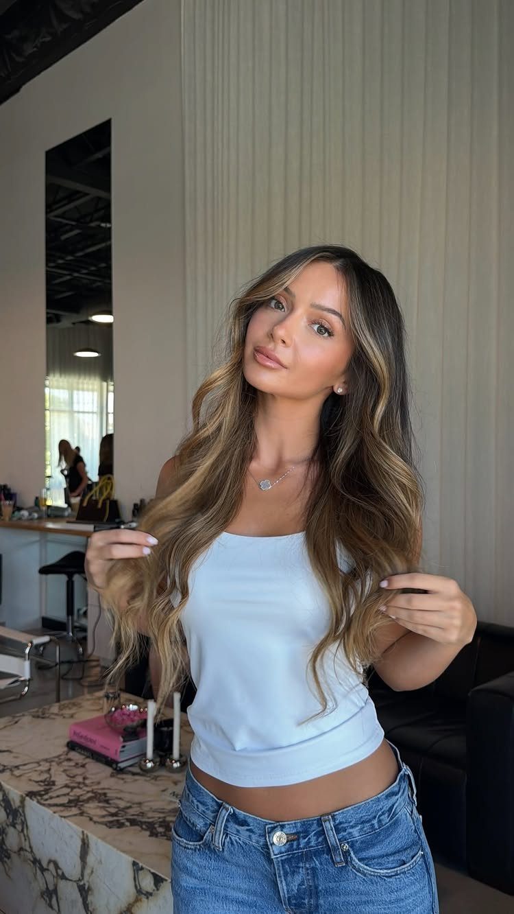 Woman displays long brown hair with lighter face-framing highlights in a salon