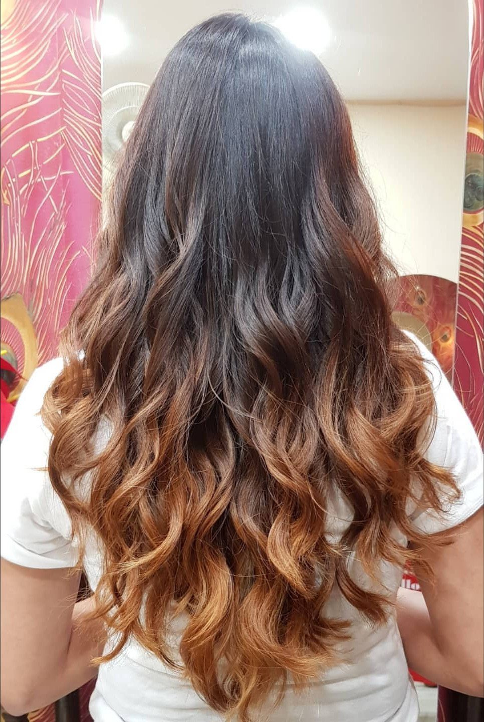 Long wavy brown hair with dark roots fading to caramel ends