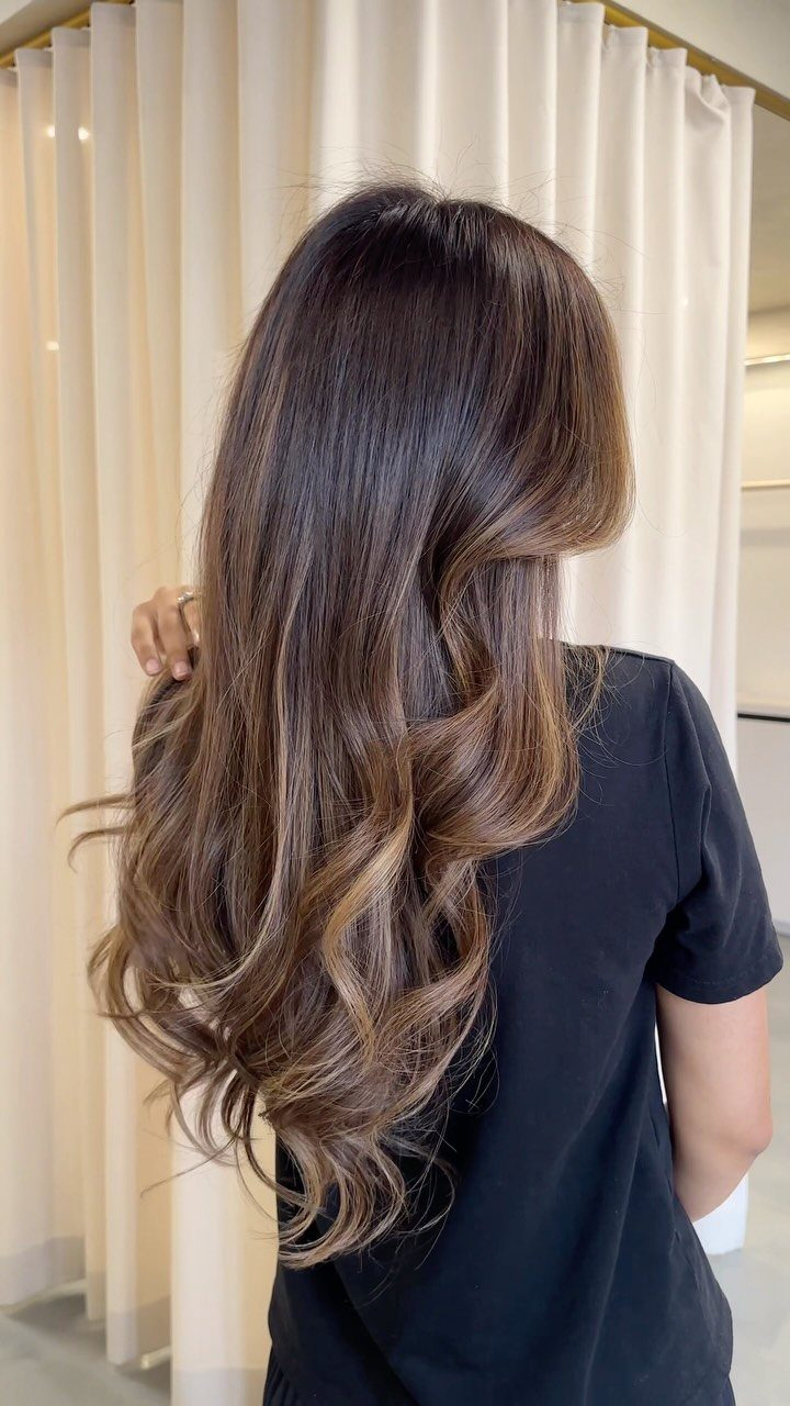 Long dark brown hair with soft toffee-toned highlights and curled ends
