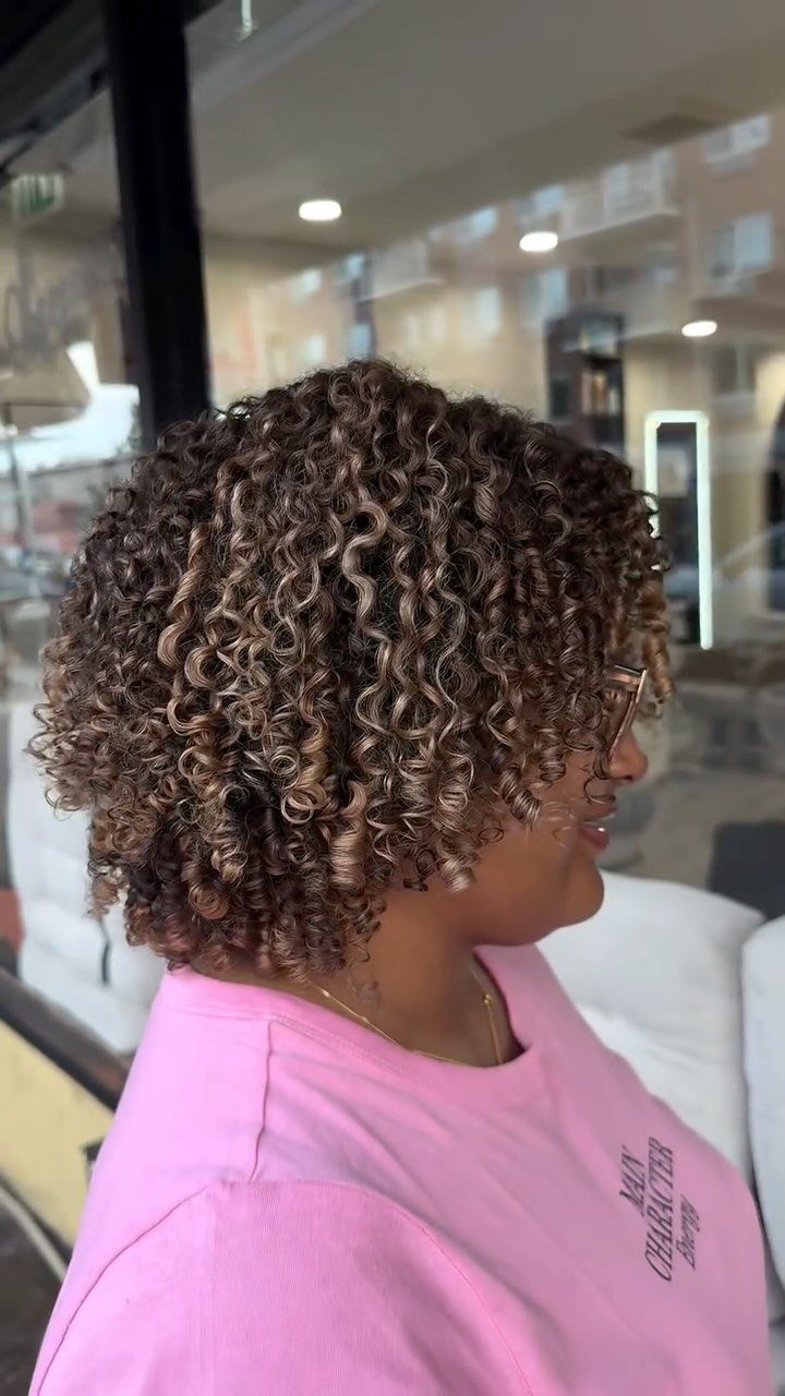 Short loose curls with subtle ash-brown highlights in a salon