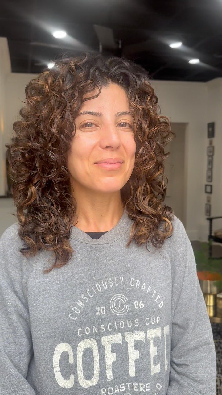 Woman with long brown curls showing lighter caramel strands around her face