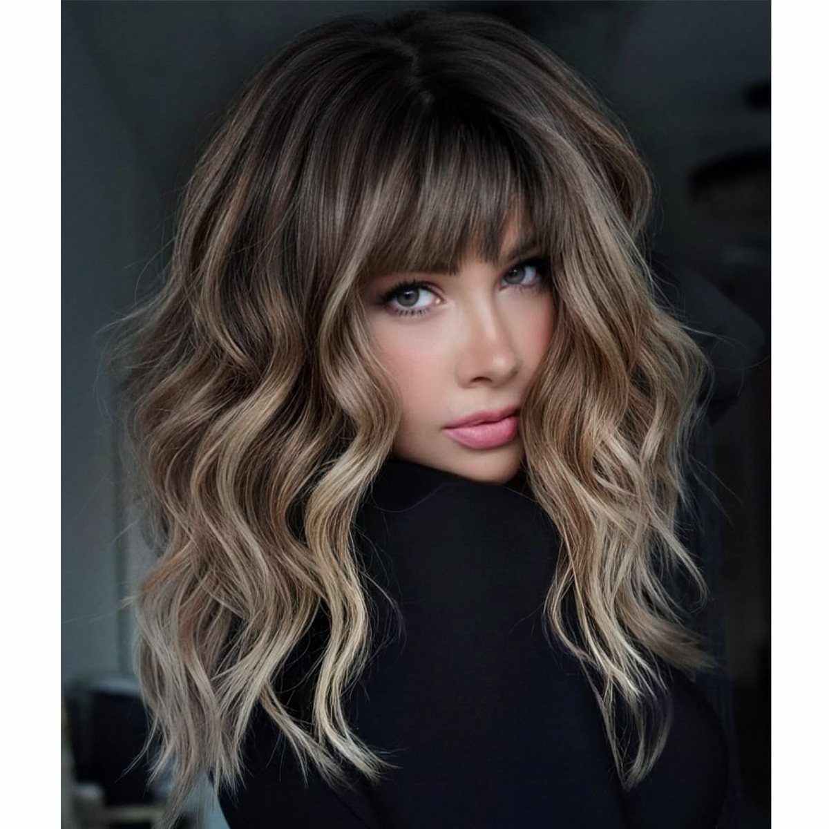 Person with long highlighted brown waves and full straight bangs