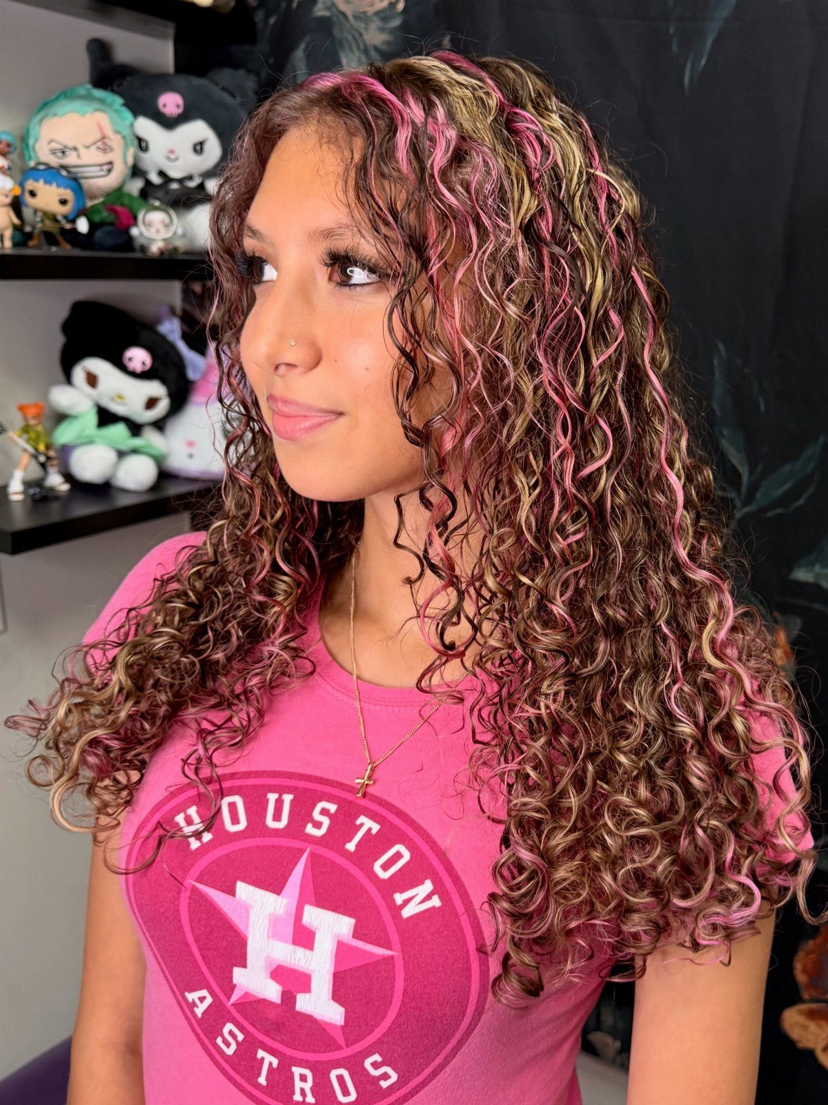 Woman with long curly brown hair featuring pink and lighter streaks