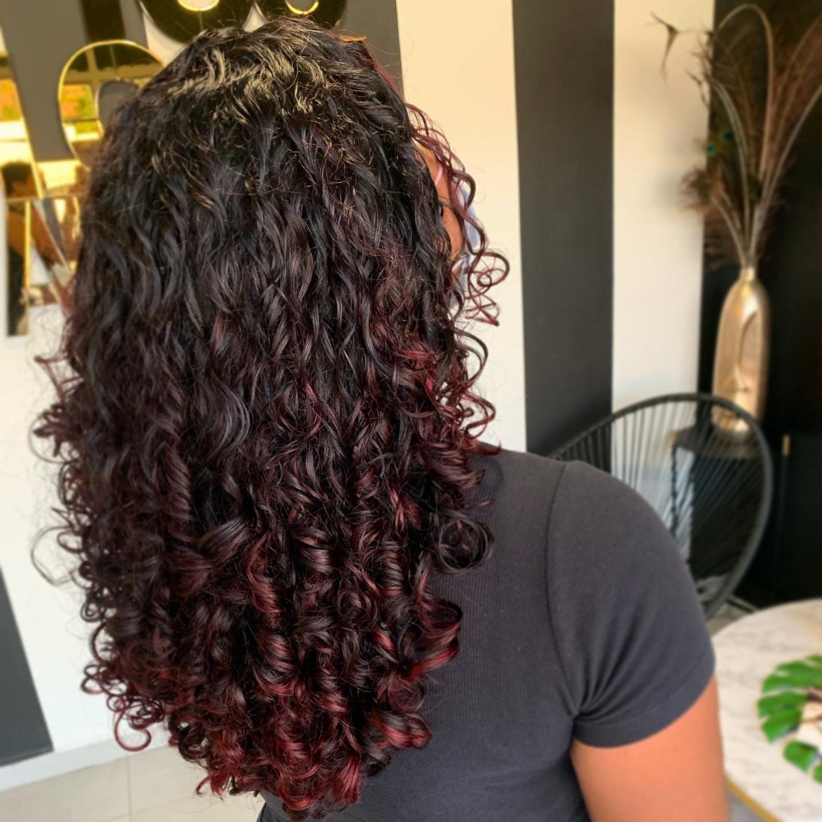 Dark curly hair with subtle red strands falls over a charcoal shirt
