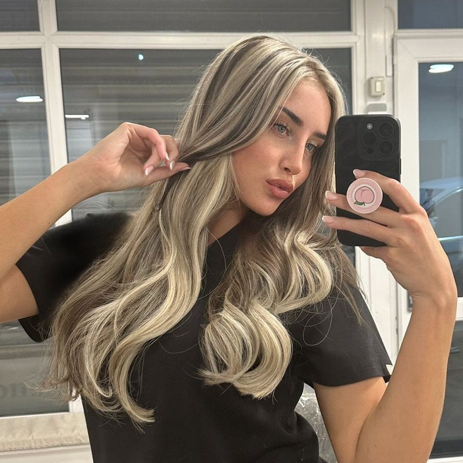 Woman displaying long wavy hair with pale blonde ribbon highlights