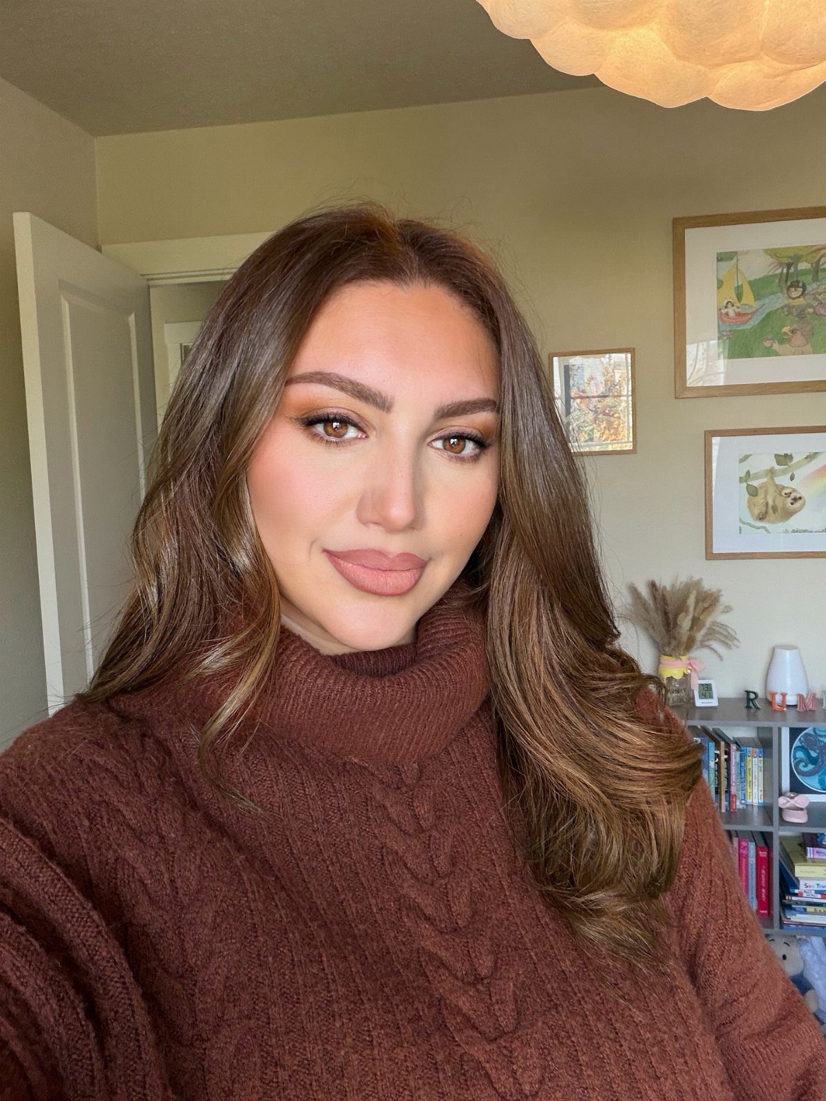 Woman with long brown hair and subtle cinnamon-toned highlights wearing a burgundy sweater