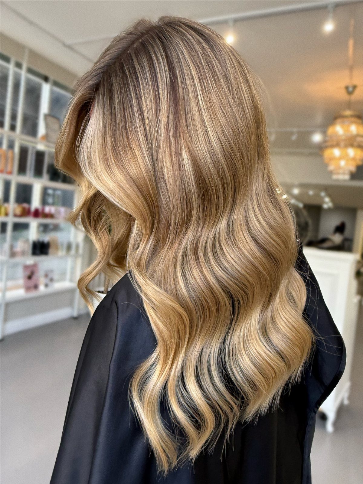 Long wavy brunette hair with chunky warm blonde highlights in a salon