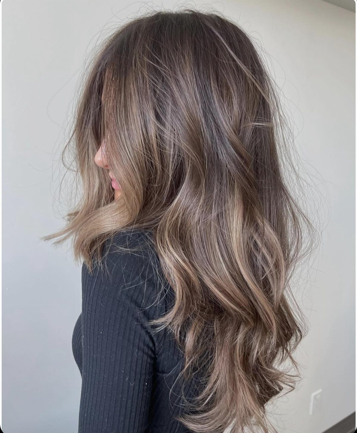 Long wavy brunette hair with cool-toned brown highlights and layered ends