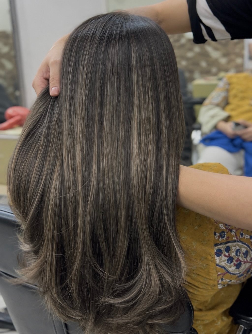 Long brunette hair with subtle hazelnut-toned highlights in a salon