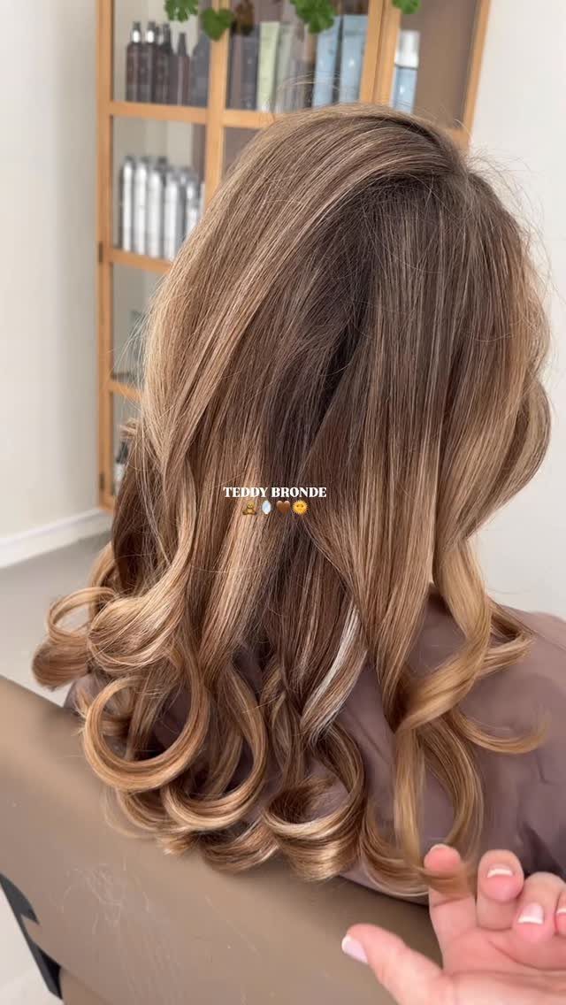Brunette curls show blended lighter and darker strands in a salon