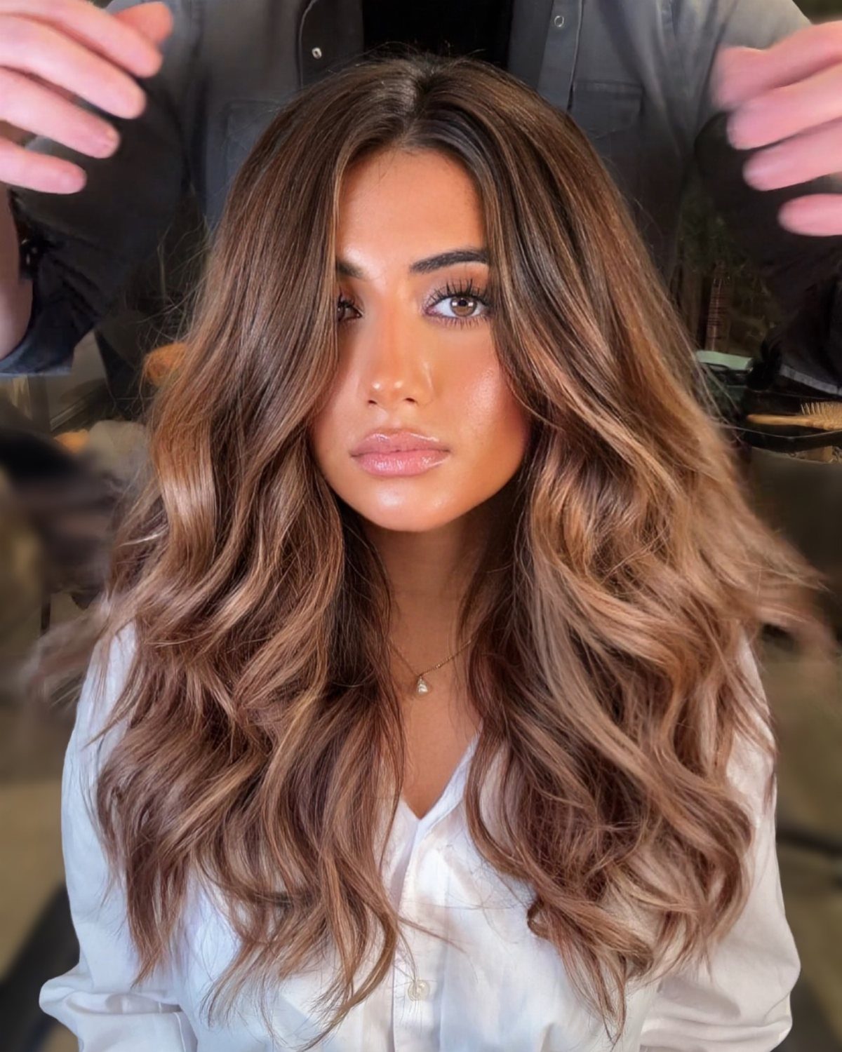 Brunette woman showing long honey caramel highlights in a salon chair
