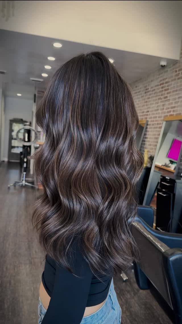 Long smoky brunette hair falls in glossy, cool-toned waves