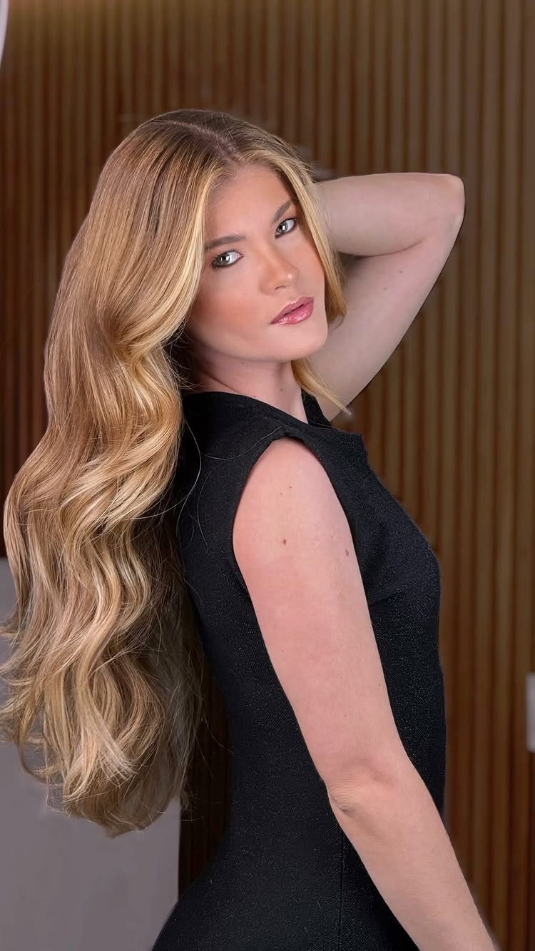Woman with long beige honey blonde waves and subtle warm highlights